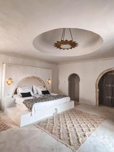 乌姆苏克Dar Naël的白色卧室配有一张大床和吊灯