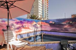 伊基克Aotea Hostel Iquique的一个带遮阳伞和椅子的庭院和一个游泳池