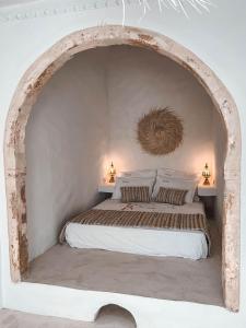 乌姆苏克Dar Naël的一间卧室设有一张大床和拱门