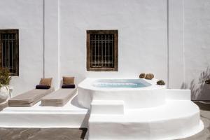 费拉On An Island suites & apartments - Fira的白色的客房设有2张长椅和热水浴池。