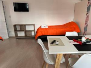 特雷利乌Apart Trelew 8的配有橙色毯子和桌子的床的房间