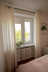 华沙Przyjazne mieszkanie w centrum Warszawy - ul Smolna的卧室设有窗户和白色窗帘