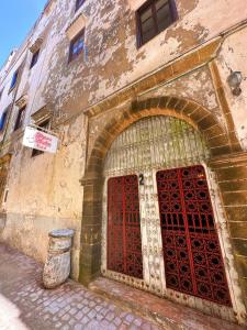 索维拉Les Terrasses d'Essaouira的一座有红色门和垃圾桶的旧建筑