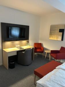 锡格堡凯撒霍夫酒店的酒店的客房配有电视、书桌和椅子。