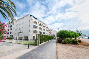 阿尔考斯布里Apartamentos La Noria Casa Azahar的海滩上的白色建筑,棕榈树