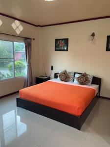 Ban Phra Trongธนวรรณรีสอร์ท - Thanawan Resort的一间卧室配有带橙色床单的床和窗户。