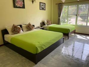 Ban Phra Trongธนวรรณรีสอร์ท - Thanawan Resort的一间卧室配有两张床,铺有石灰绿色床单