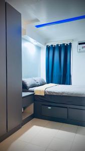 马尼拉Staycation in Pasig Love Never Fails的一间卧室配有两张床和蓝色窗帘