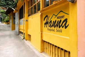 帕纳哈切尔Hotel & Restaurante Hanna Resort的黄色的建筑,旁边标有标志
