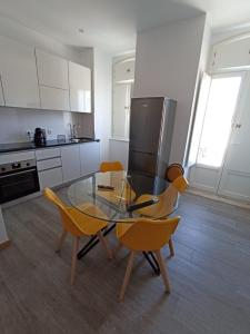 科英布拉FAMILY APARTAMENT II的厨房配有玻璃桌和黄色椅子