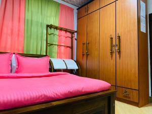 卡图纳耶克ANTONIO TRANSIT KATUNAYAKE的一间卧室配有一张带粉色床单和木制橱柜的床。