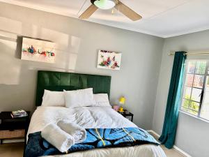LobambaWeMukelekile (you are welcome)的一间卧室配有一张带绿色床头板的床