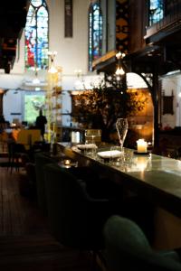 阿纳姆Boutiquehotel The Church的餐厅设有酒吧,提供玻璃杯和蜡烛