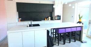 安特卫普Mooi vakantiehuis tussen Breda, Antwerpen, Gent & Hasselt的厨房配有白色橱柜和紫色吧台凳