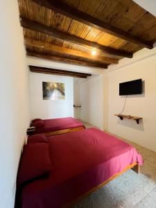 洛佩斯港COLIBRI GUEST HOUSE的一间卧室配有红色的床和一台平面电视