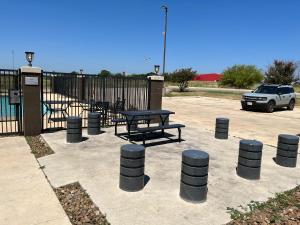 PearsallStudio 6 Suites Pearsall TX的围栏旁停车场的野餐桌