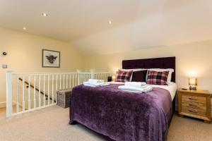 阿尼克Birsley Cottage的一间卧室配有一张带紫色毯子的大床