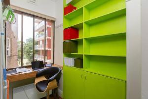 悉尼Tranquil 1 Bedroom Apartment - Rushcutters Bay Self-Catering的办公室设有绿色的书架、桌子和椅子