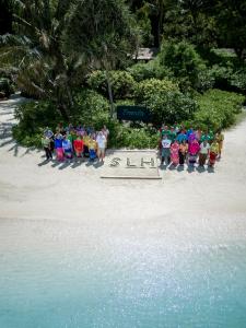 皮皮岛Zeavola Resort的一群人站在海滩上的一个标志旁边