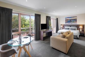 墨尔本Kimberley Gardens Hotel, Serviced Apartments and Serviced Villas的酒店客房带一张床、一张桌子和椅子