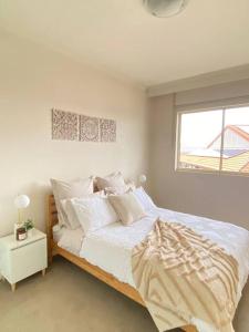 悉尼Apartment in Chiswick with Pool, sauna & Gym的一间卧室配有一张带白色床单的床和一扇窗户。
