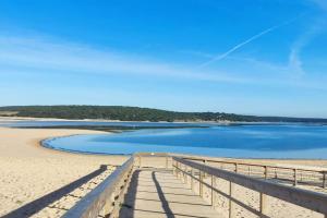 塞辛布拉Calma na Lagoa de Albufeira, Castelo Sesimbra.的蓝色海滩上的码头