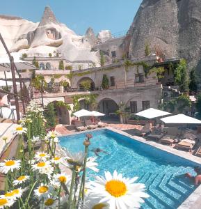 格雷梅本地岩洞酒店的一个带鲜花和遮阳伞的游泳池的度假酒店