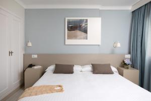 罗萨斯阳光与海滩名誉酒店的卧室配有一张带两个枕头的大白色床
