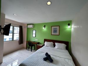 马六甲Hotel Harbour Stay的一间卧室设有绿色的墙壁、一张床和一张书桌