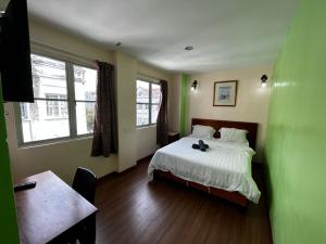 马六甲Hotel Harbour Stay的一间卧室配有一张床、一张桌子和两个窗户