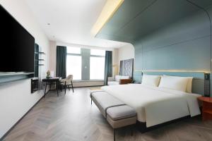 兰州兰州亚欧国际高空亚朵S酒店的卧室配有一张白色的大床和一张沙发。