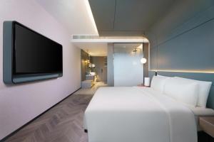 兰州兰州亚欧国际高空亚朵S酒店的卧室配有白色的床和平面电视。