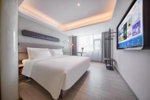 惠州惠州金山湖港惠轻居酒店的一间酒店客房,配有白色的床和一台平面电视