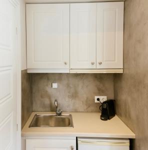 卡利斯托斯Ammos Luxury Suite的厨房配有白色橱柜和水槽