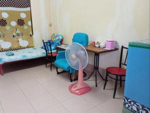 达叻府NP guesthouse的客房配有桌子和粉红色风扇。