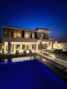 半月湾Al Qand Chalet For Families Only的一座在晚上设有游泳池的大房子