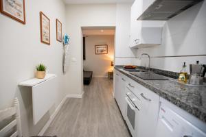 塞维利亚Apartamentos Doña Concha的厨房配有白色橱柜和水槽