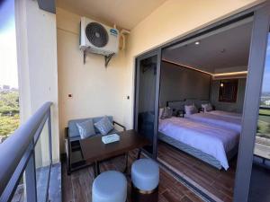 三亚中州国际公寓(三亚湾凤凰机场店)的一间带一张床和一张书桌的卧室以及一个阳台