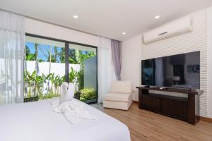 Ban Phru ChampaEscape Villas - Luxury Pool Villa at Anchan Villas的卧室配有一张白色大床和电视。