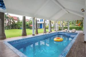 加尔各答Timeless Elegance by StayVista - Poolside Villa with Lawn & Terrace的中间设有木筏的游泳池