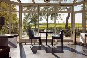 塞兰Van der Valk Golfhotel Serrahn - Adult Only的窗户前的温室配有桌椅