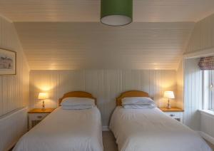 格伦科Duart Cottage的配有两盏灯的小房间内的两张床