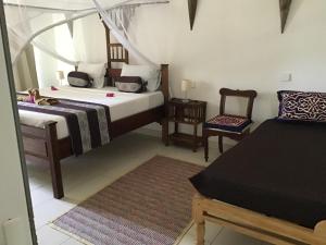 普瓦尼梅查恩加尼Nakupenda Malaika Flat的一间卧室配有两张床和椅子