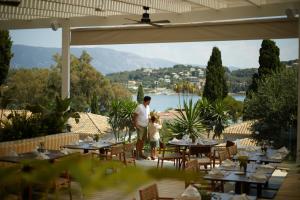 古维亚Dreams Corfu Resort & Spa - All Inclusive的男人和孩子站在带桌子的庭院