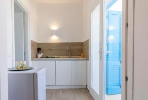 马里迪莫Tenuta Pezzeselle - Casa Vacanze的厨房配有白色橱柜和蓝色窗户。