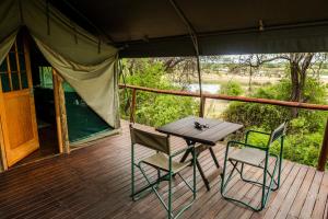 龙杜Taranga Safari Lodge的帐篷内的木制甲板上配有桌椅