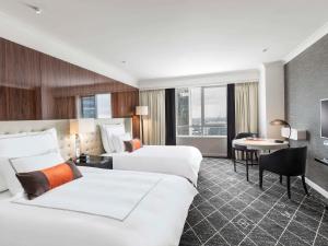 悉尼Swissotel Sydney的酒店客房配有两张床和一张书桌