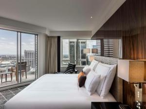 悉尼Swissotel Sydney的卧室设有一张白色大床和大窗户