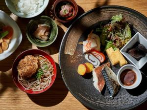 富山Daiwa Roynet Hotel Toyama-Ekimae的餐桌,带面条和其他食物的盘子