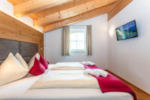 玛丽亚阿尔姆Appartements Ferienwohnungen Unser Unterberg的一间卧室配有一张带红色枕头的大床